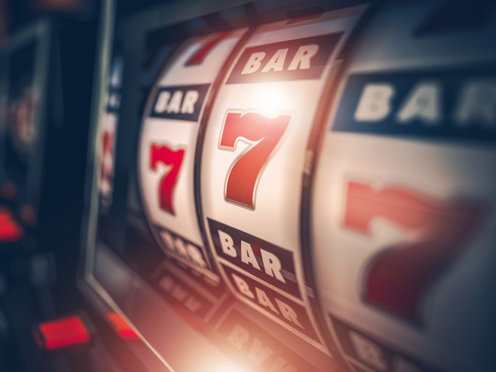 회전하는 릴 화면에 숫자 7과 BAR 기호가 정렬된 모습으로 슬롯머신 확률과 슬롯머신 환수율의 상관관계를 설명하는 인라인 이미지